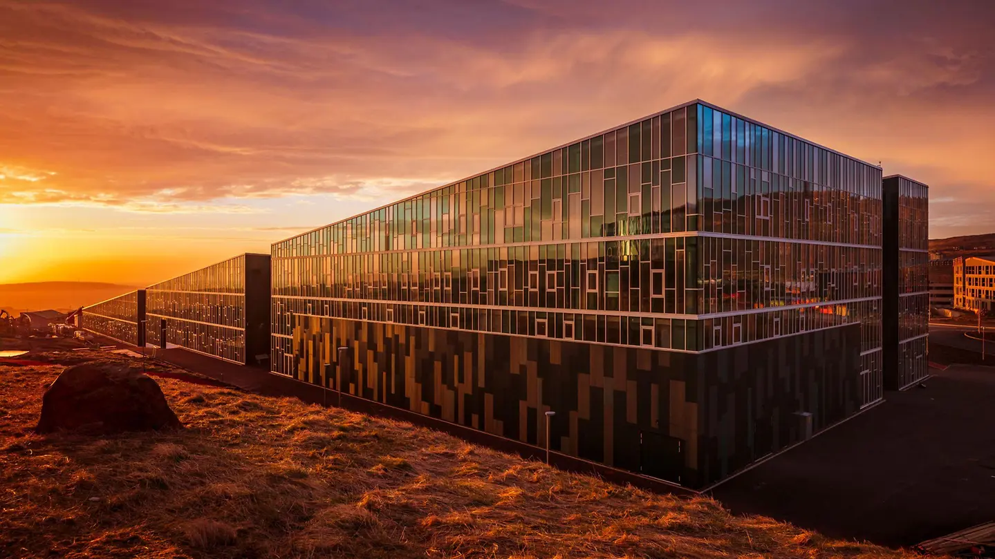 Schüco FWS 50 glass façade reflecting a dramatic sunset