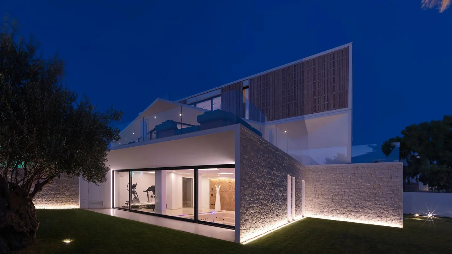 Modern residence with a minimal-frame Schüco sliding glass façade at night